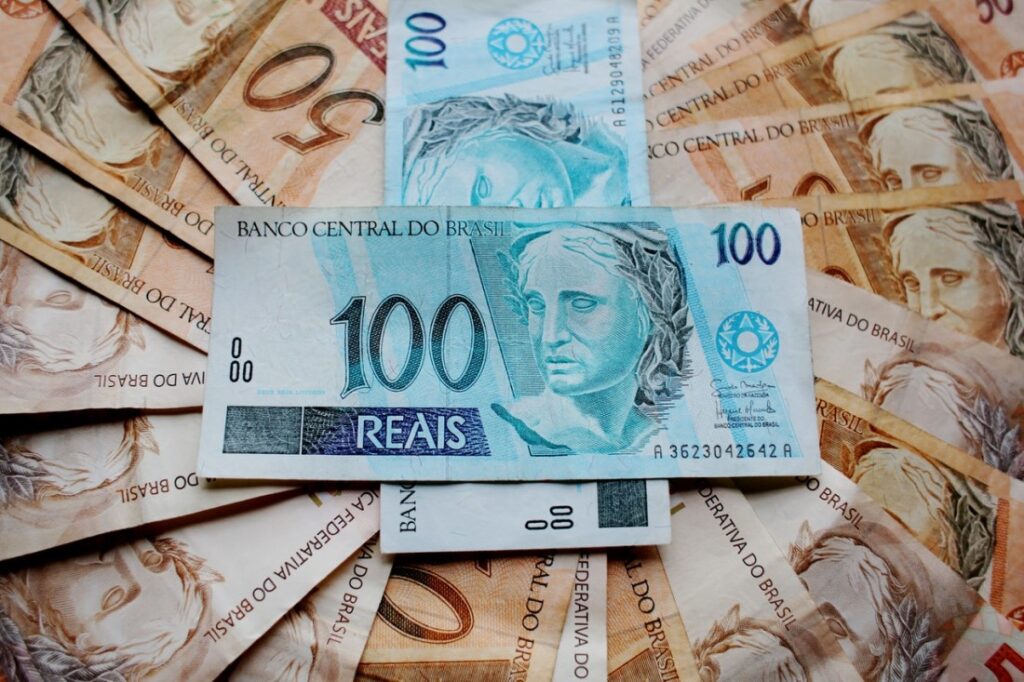 Várias notas de R$50,00 sobrepostas, formando um círculo, e mais duas notas de R$100,00 no centro.
