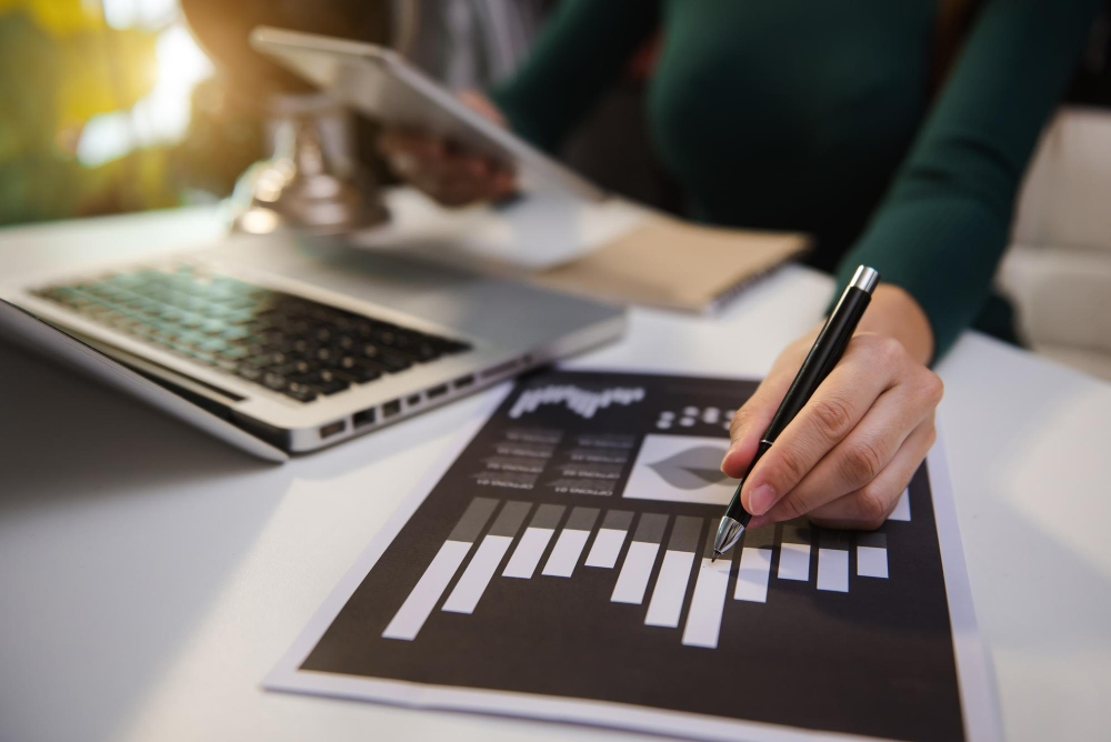 Documentos de negócios na mesa de escritório com smartphone e tablet digital e gráfico financeiro e mulher trabalhando para ilustrar então artigo sobre as principais dicas para fazer um planejamento tributário eficiente na sua empresa