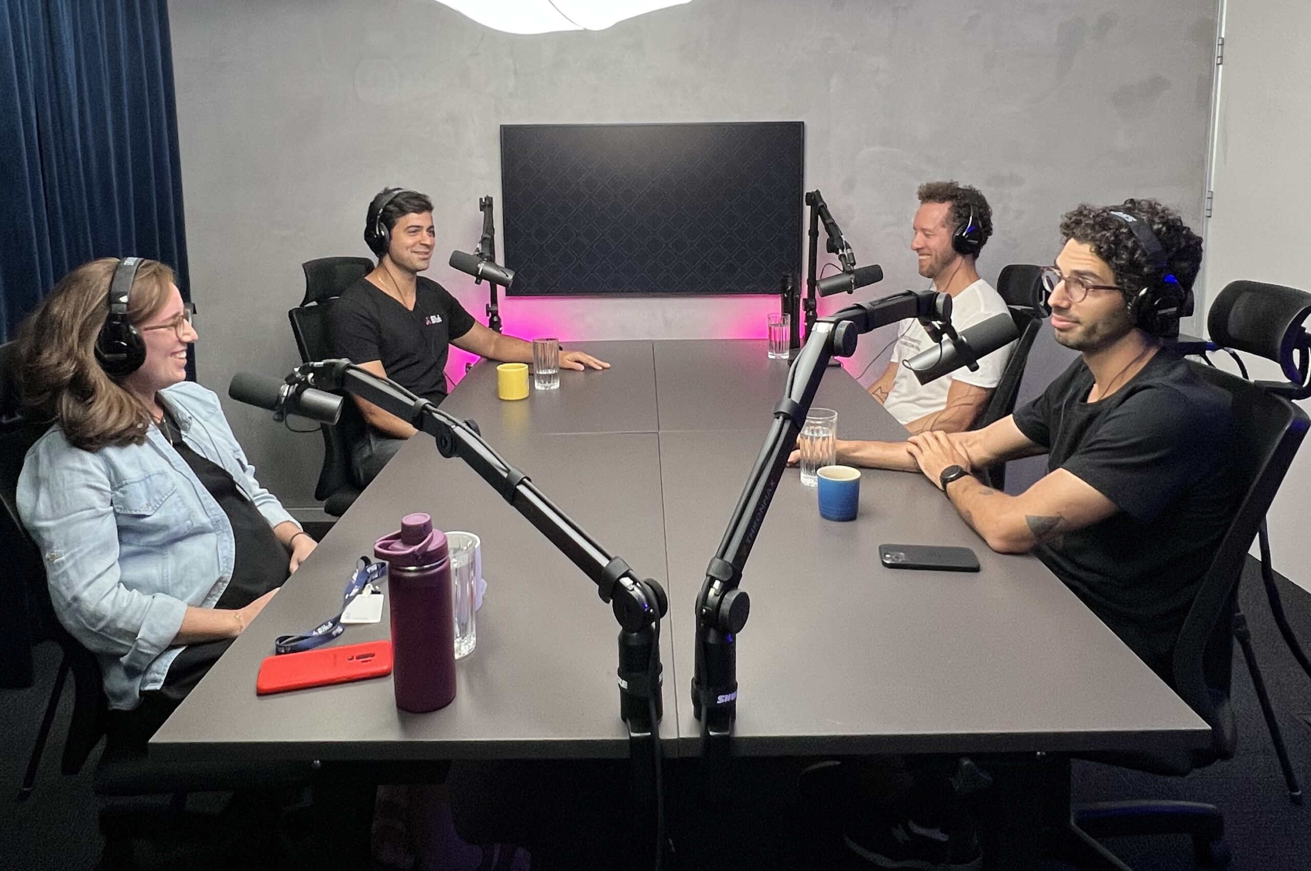 Fundadores da BHub sentados em volta de uma mesa, em um estúdio de podcast.