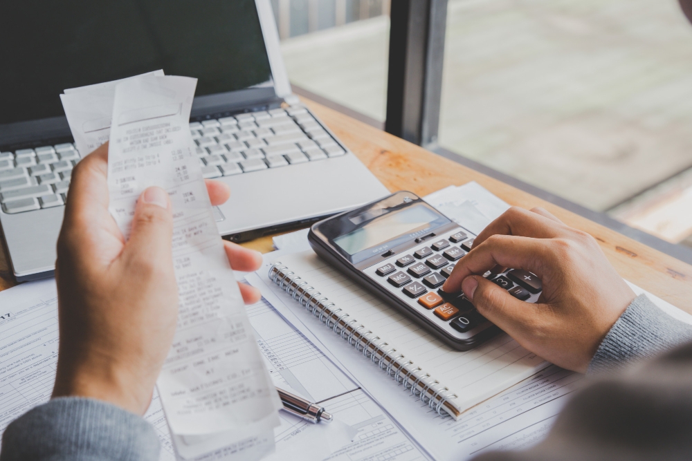 Foto o homem novo que usa a calculadora e calcula contas no escritório domiciliário para ilustrar assim artigo sobre como a contabilidade financeira pode ajudar sua empresa a tomar decisões mais assertivas.