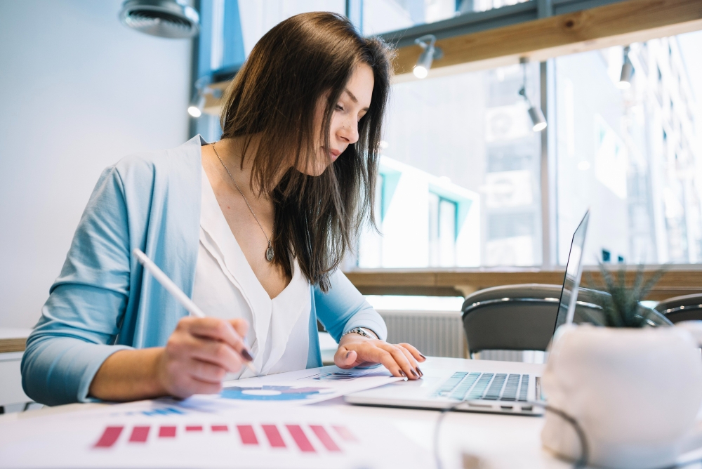 Mulher com caneta usando laptop para ilustrar assim artigo sobre planejamento financeiro para startup