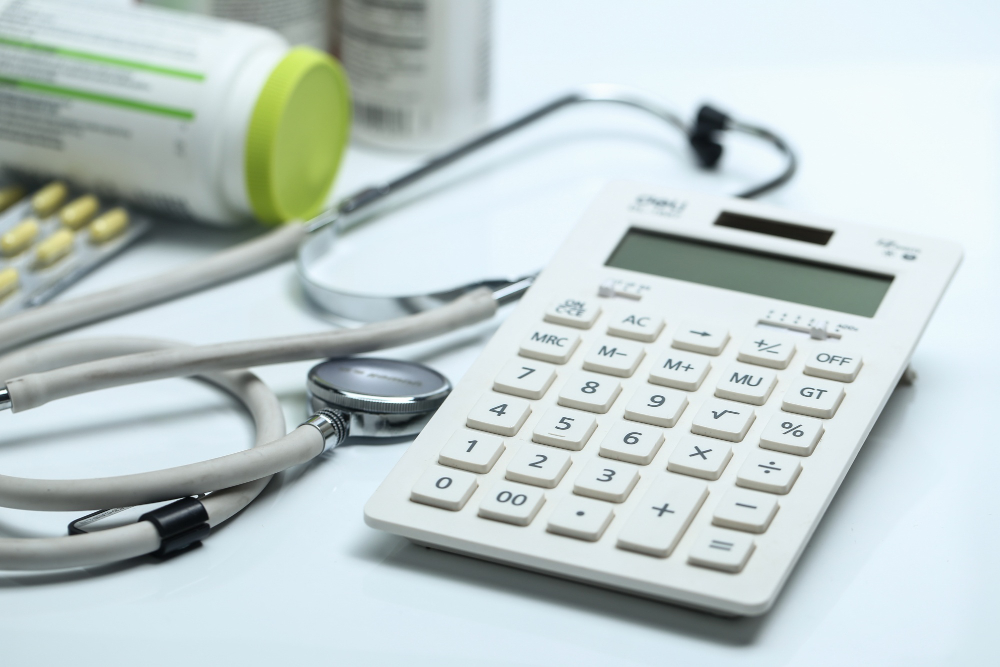 calculadora, estetoscópio e remédios no fundo branco para ilustrar assim artigo sobre contabilidade para clínicas médicas