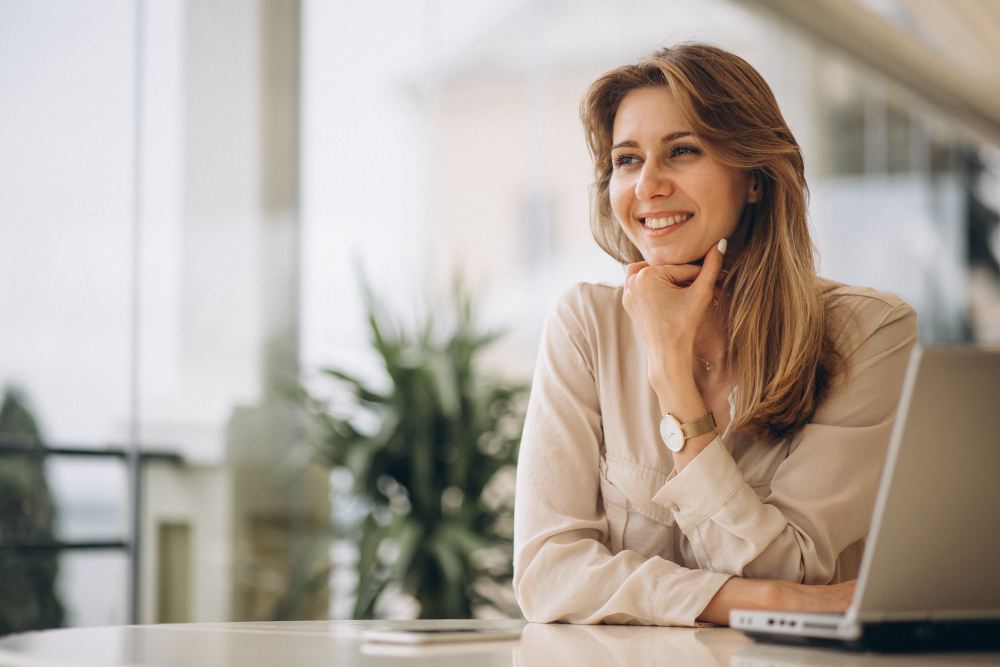 Foto de mulher de negócios sorrindo em frente ao notebook para ilustrar assim artigo sobre o papel do CFO as a Service na análise de demonstrações financeiras