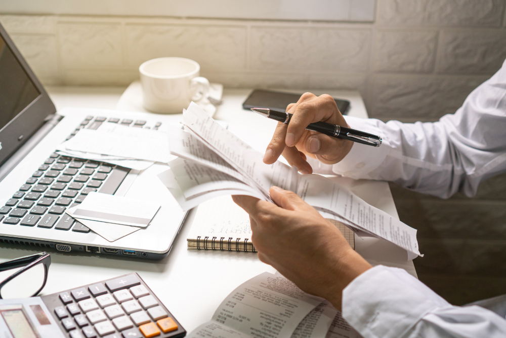 Um homem de negócios, segurando a caneta enquanto olha para as contas em seu local de trabalho para ilustrar artigo sobre o que é contabilidade de custos