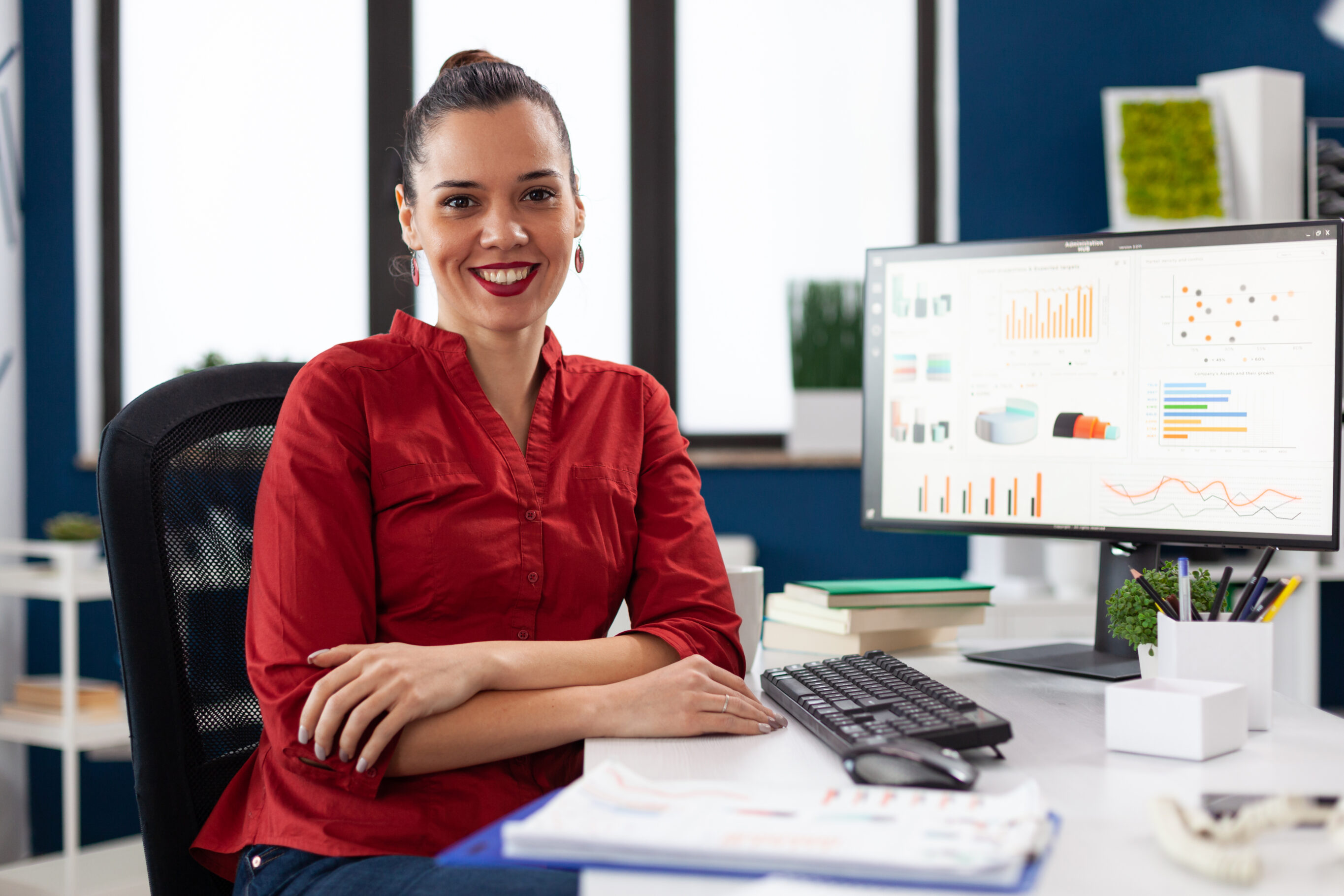 Foto retrato de mulher de negócios em um escritório corporativo, sentada na mesa, sorrindo para a câmera para ilustrar assim artigo sobre como aumentar carteira de clientes de um escritório de contabilidade