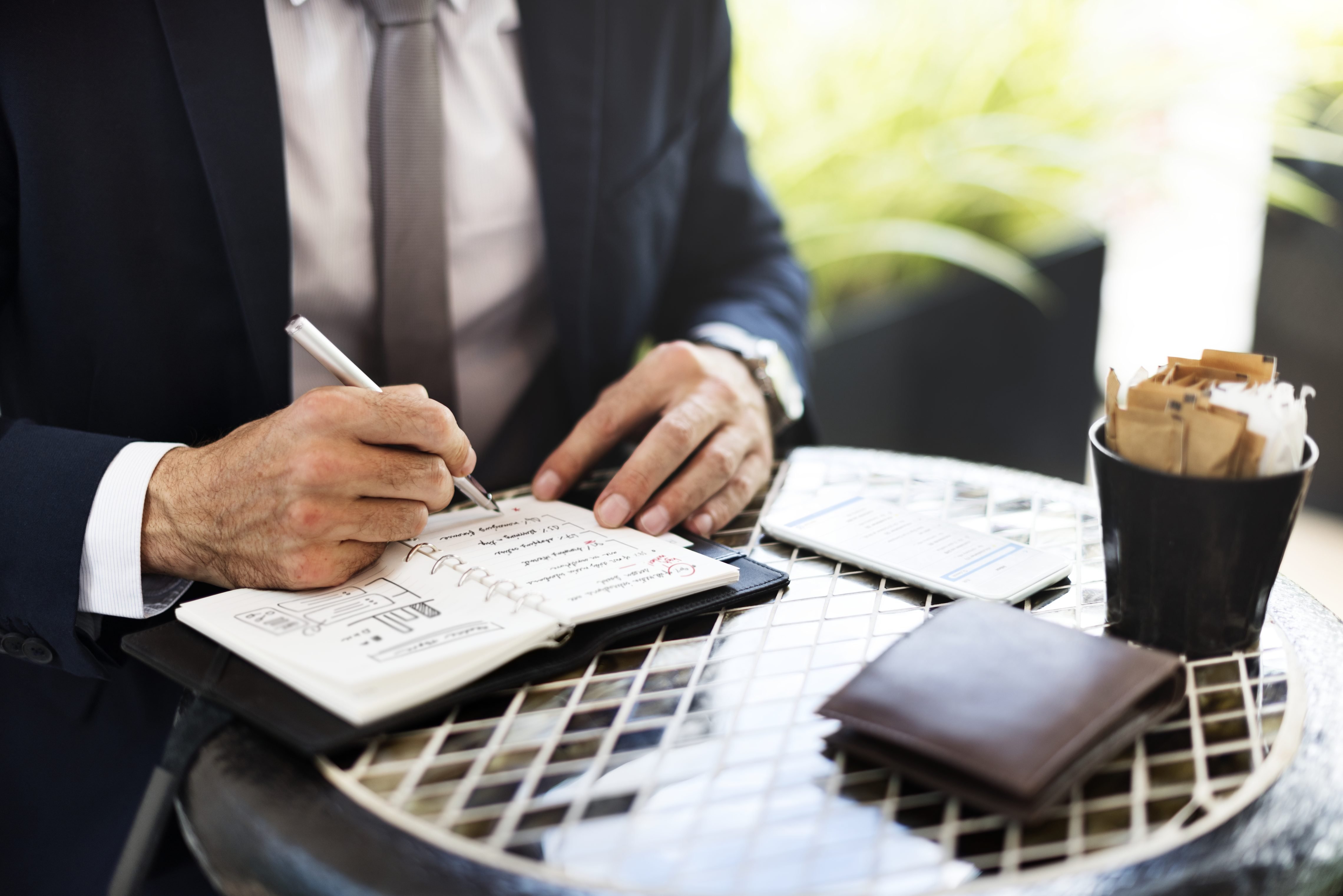 Empreendedor assina documentos de abertura de empresa em mesa com computador e papéis