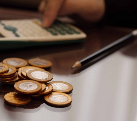 Counting brazilian money, real coins. Calculator and pen in blurred background.